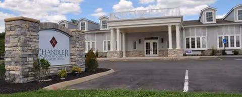 Exterior view of Cardinal Landing Memory Care facility with a stone sign, driveway, and entrance.