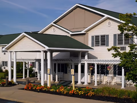 Peregrine Senior Living at Shaker exterior shows a covered entrance and colorful flowers.
