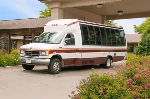 A white and maroon passenger bus parked outside Life Care Center of Omaha.