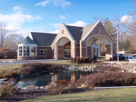 Manoogian Manor exterior: brick building with arched entrance and a pond in front.