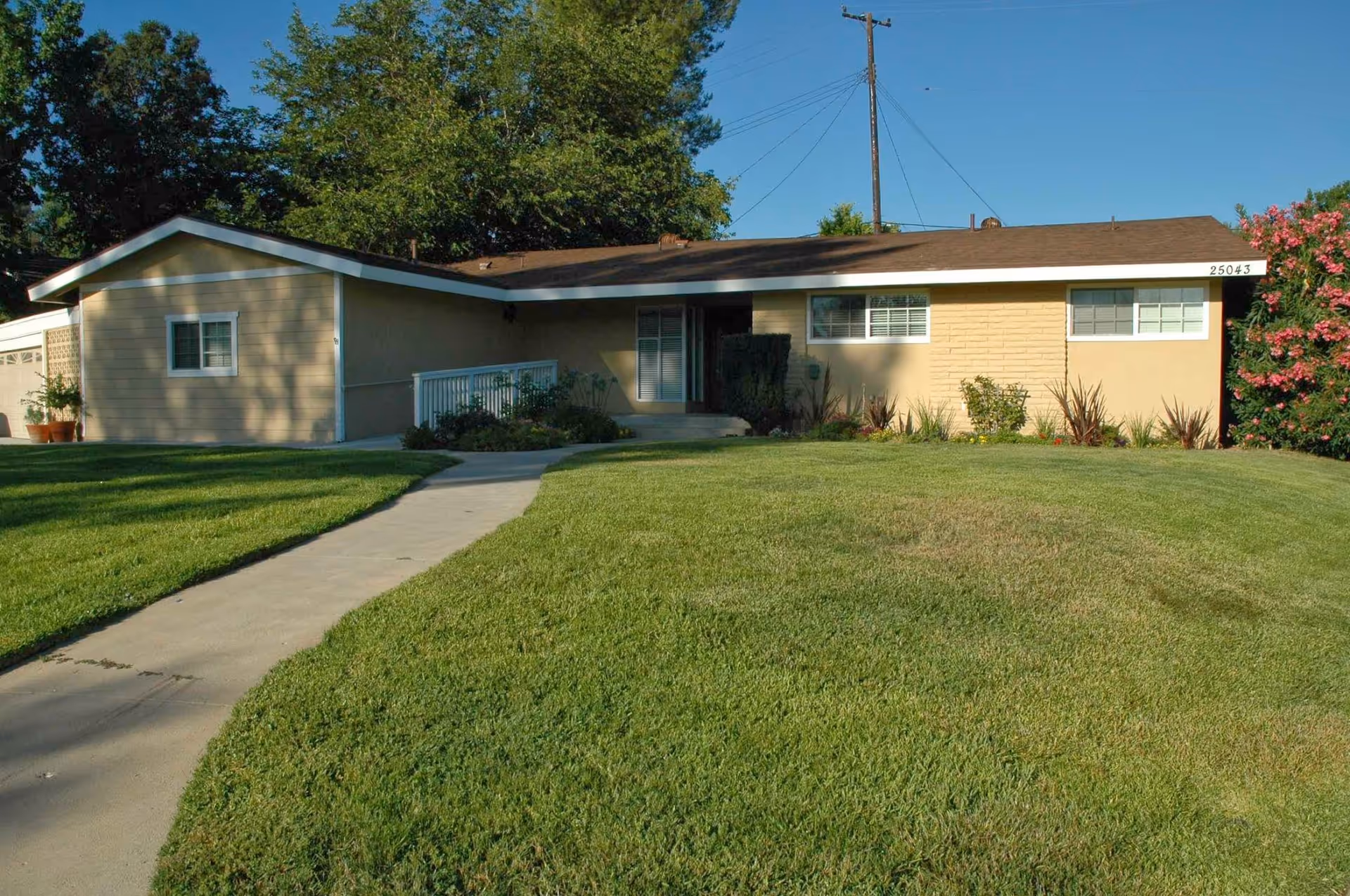 Single-story ranch-style house with a manicured front lawn and a walkway leading to the main entrance.