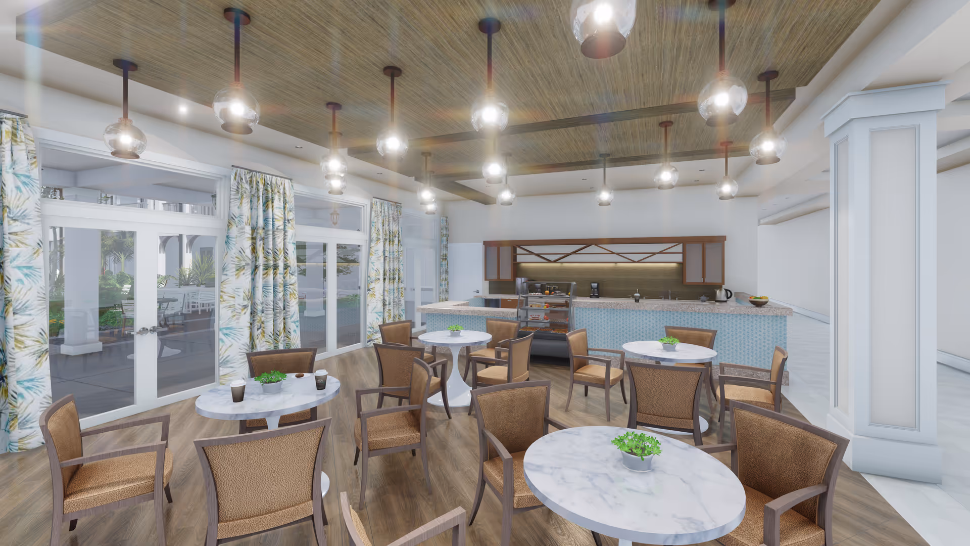 A bright dining area with several round marble-top tables surrounded by brown cushioned chairs. The room features a wooden floor and ceiling with multiple hanging globe pendant lights. Large windows with floral curtains let in natural light and provide a view of an outdoor patio with seating. At the back, there is a counter with a display case containing pastries and a coffee machine.