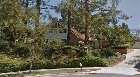 Exterior view of Bardwell Pines Country Homes with trees, shrubs, and a curved driveway.