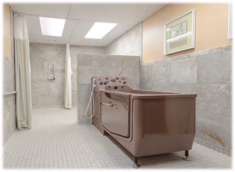 A spacious bathroom with beige tiled walls and floor, featuring a large brown assisted bathing tub with control knobs and a handheld shower. There is a walk-in shower area with a curtain and a wall-mounted showerhead. A framed picture hangs on the wall above the tub.
