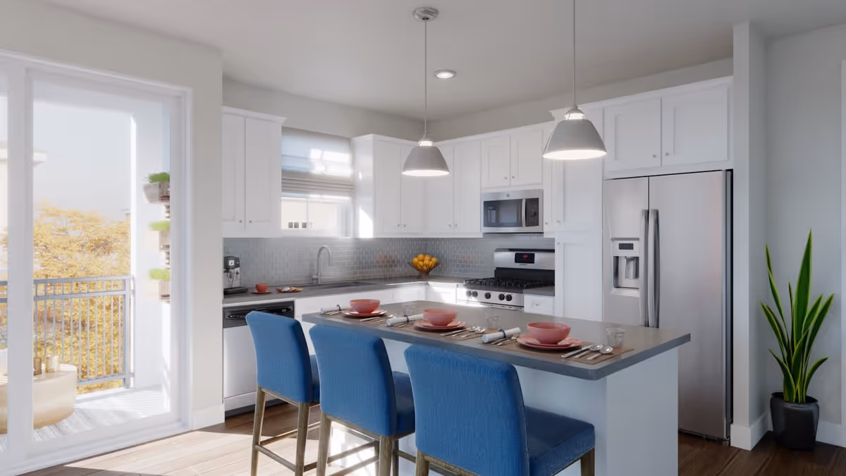 Modern kitchen with white cabinets, stainless steel appliances including a refrigerator, stove, and microwave. A kitchen island with a gray countertop is set with pink bowls, plates, and silverware, accompanied by three blue upholstered bar stools. Two pendant lights hang above the island. A sliding glass door leads to a balcony with outdoor seating and plants. A tall green plant is placed in a black pot near the refrigerator.