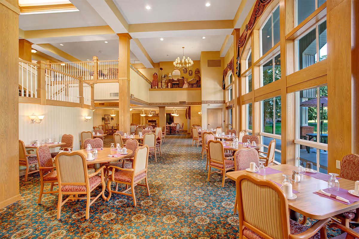 Bright, spacious dining room with multiple set tables, large floor-to-ceiling windows and high ceilings.
