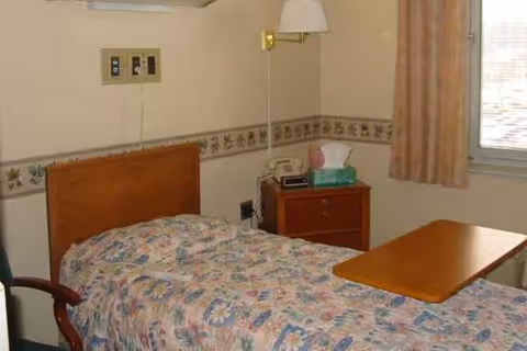 Small bedroom in a senior facility with a single bed and nightstand.