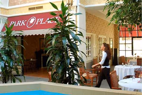 Outdoor courtyard of Park Place Nursing & Rehabilitation Center with tables, chairs, and a passerby.