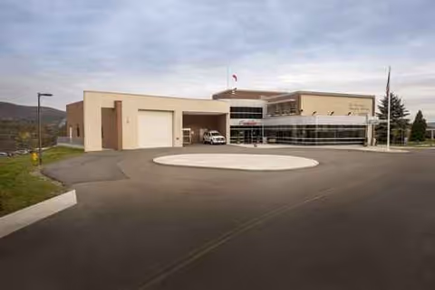 Exterior view of a modern senior facility with circular driveway and glass entrance.
