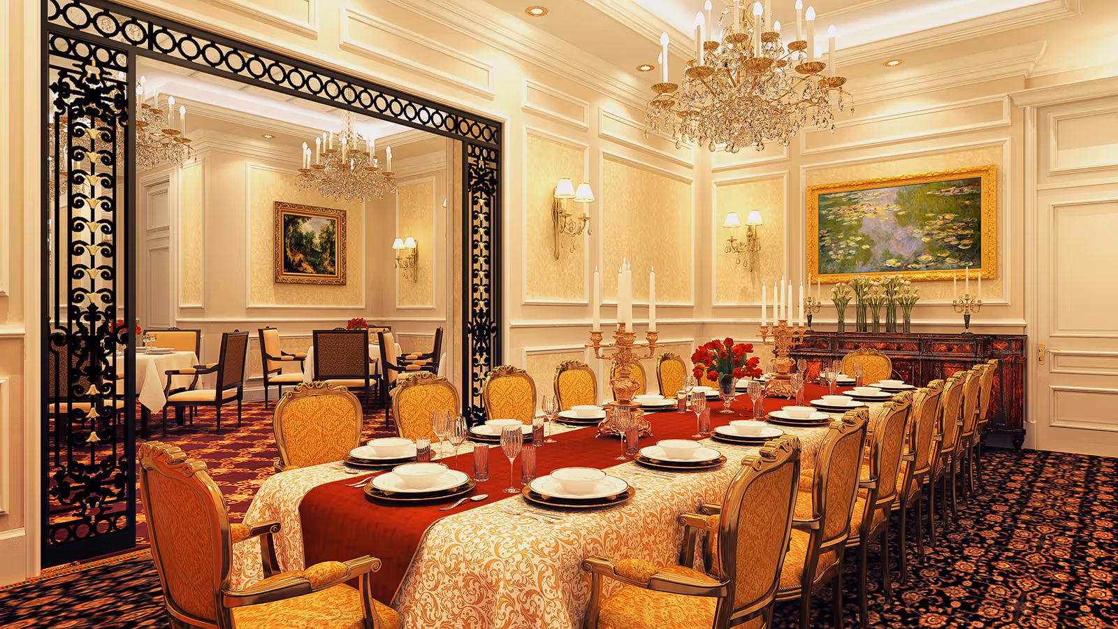 Elegant dining room with a long table set for a formal meal, featuring ornate gold chairs, white and red tablecloths, multiple place settings with plates and glasses, tall candle holders, and floral centerpieces. The room has chandeliers, framed paintings on cream-colored walls, and a patterned carpet. A large decorative black metal frame separates this room from another dining area in the background.