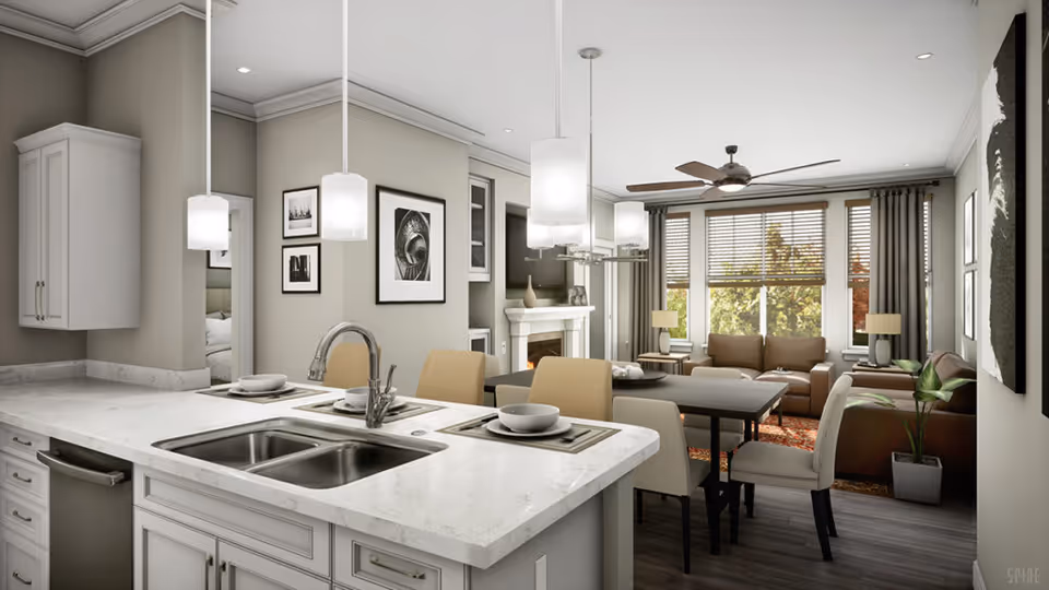 A modern open-concept living space featuring a kitchen island with a double sink and two place settings. The kitchen opens into a dining area with a table and four chairs, and a living room with two brown sofas, a coffee table, a fireplace, large windows with blinds, and ceiling fan. The walls are decorated with framed black and white artwork, and the room is well-lit with pendant lights and natural light from the windows.