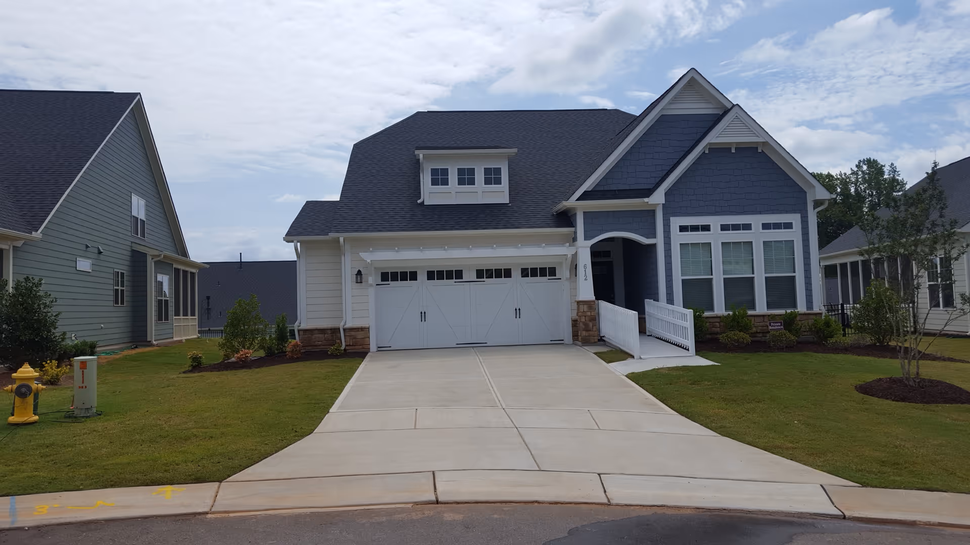 Front view of a detached house with a two-car garage, driveway, and landscaped lawn.