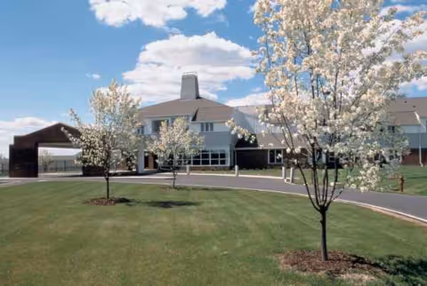 Exterior front view of Kendal at Ithaca with blooming trees and green lawn.