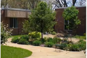 Brick senior living facility exterior with a landscaped courtyard and benches.