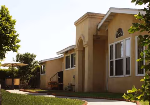 Exterior view of Eternal Life Assisted Living with beige building, arched doorway, and outdoor seating.