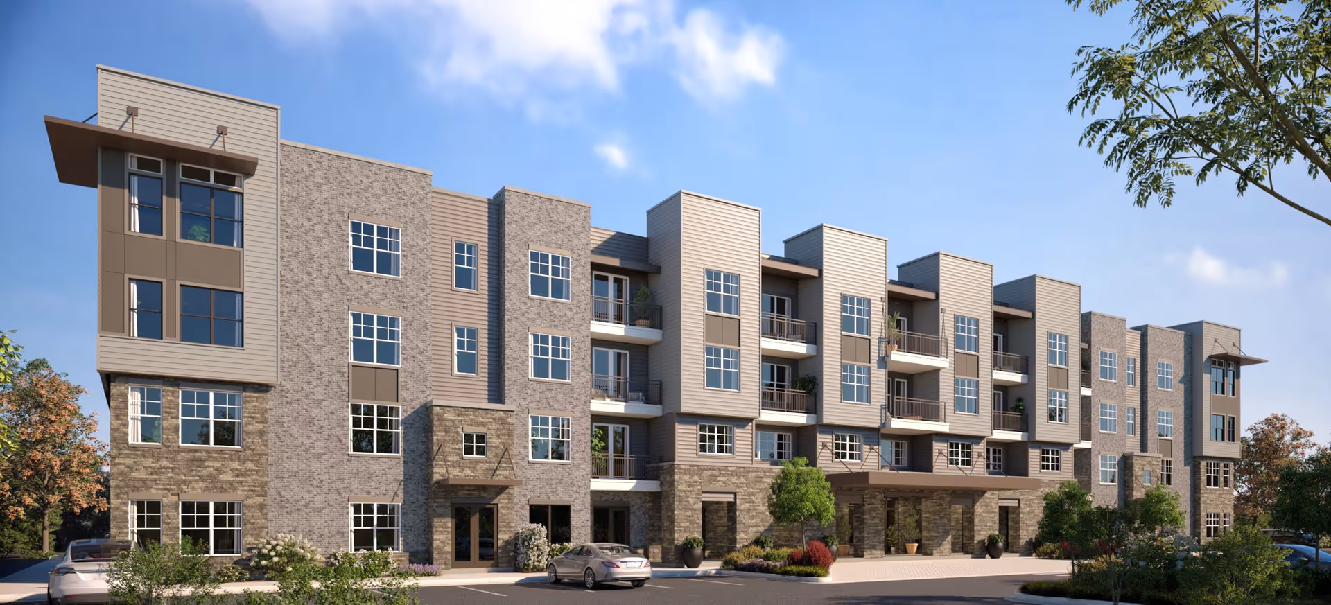Exterior view of a modern multi-story residential building with large windows, balconies, and a mix of stone and siding facade under a blue sky with some clouds. There are cars parked in front and landscaped greenery around the building.