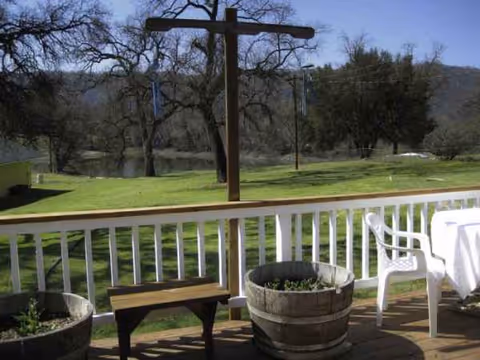 Outdoor deck with a tall wooden cross-shaped frame, planters, and patio seating.