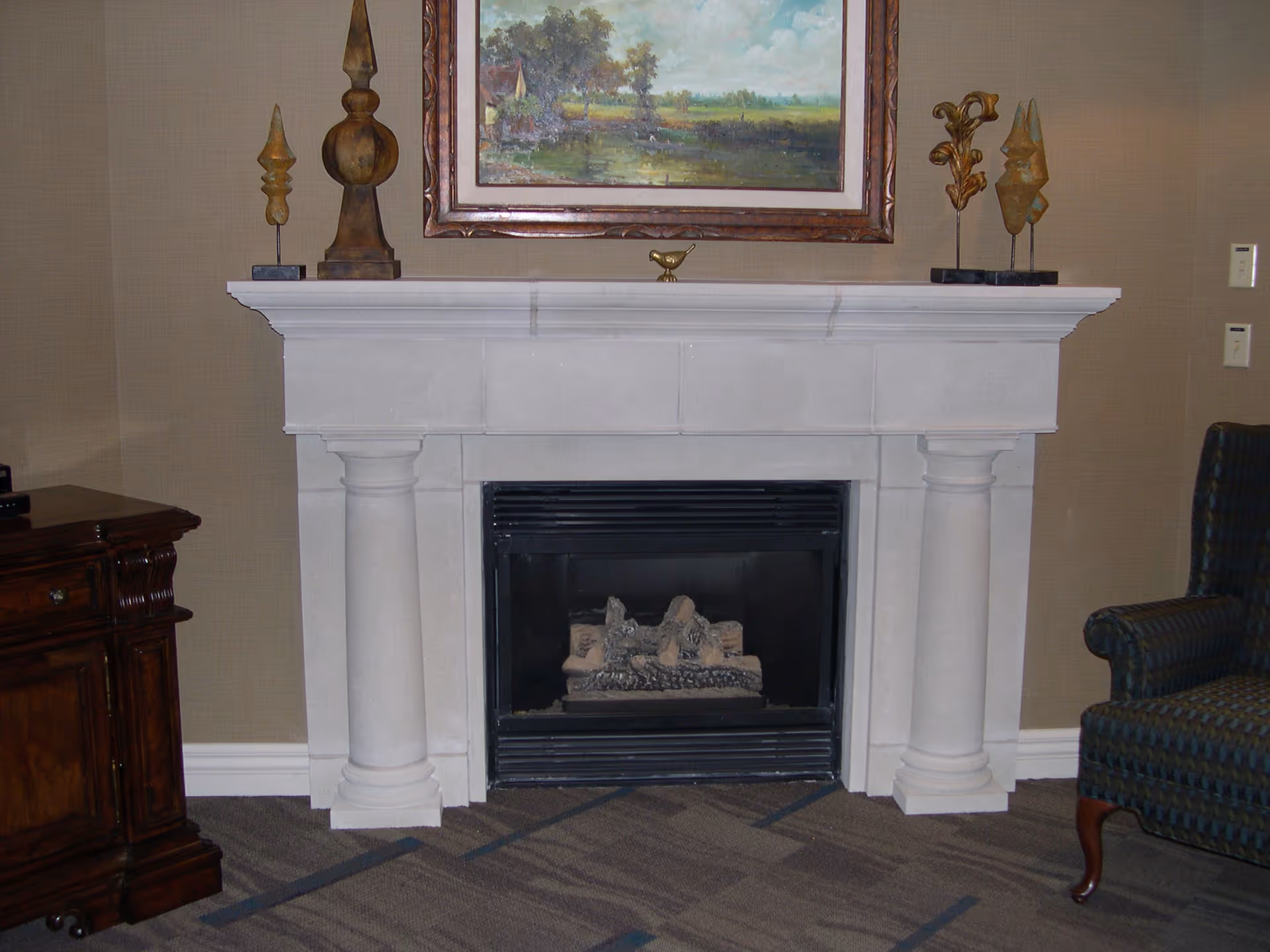 A decorative fireplace with a painting above, accompanied by furniture and decor items.