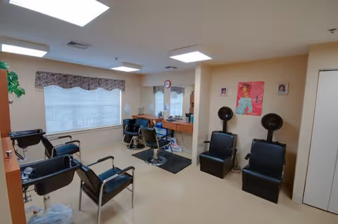 Interior salon room with styling chairs, mirrors, shampoo sinks and hooded hair dryers.