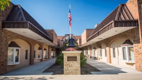 Exterior courtyard view of Generations Senior Living of Berea with brick wings and flagpole.