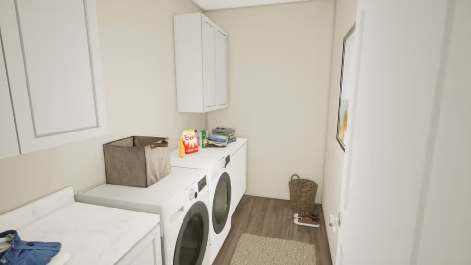 A bright laundry room with side-by-side front-loading washer and dryer, white cabinets, detergent and laundry baskets.