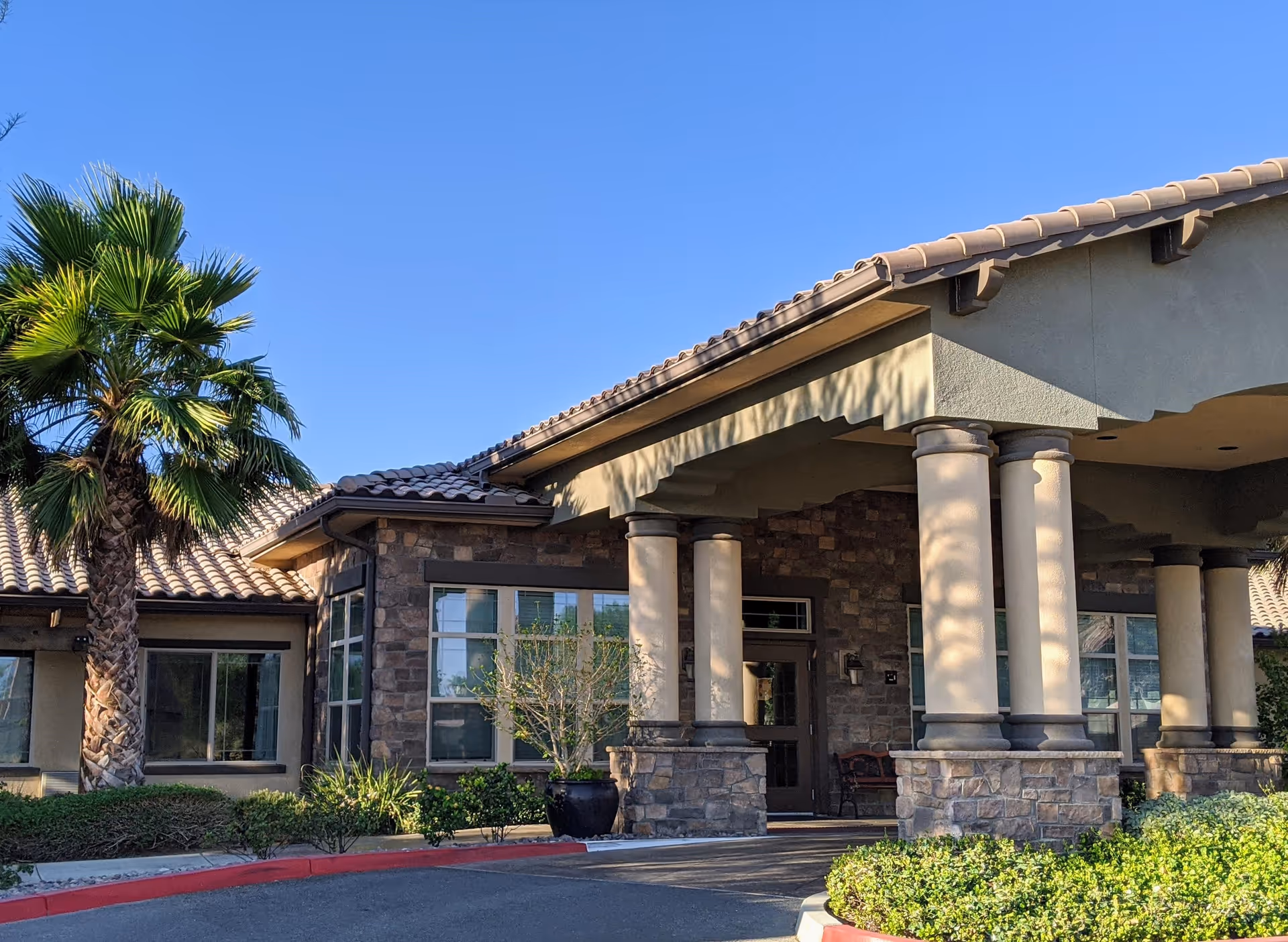 Front exterior of Caleo Bay Assisted Living and Memory Care with columns and palm tree