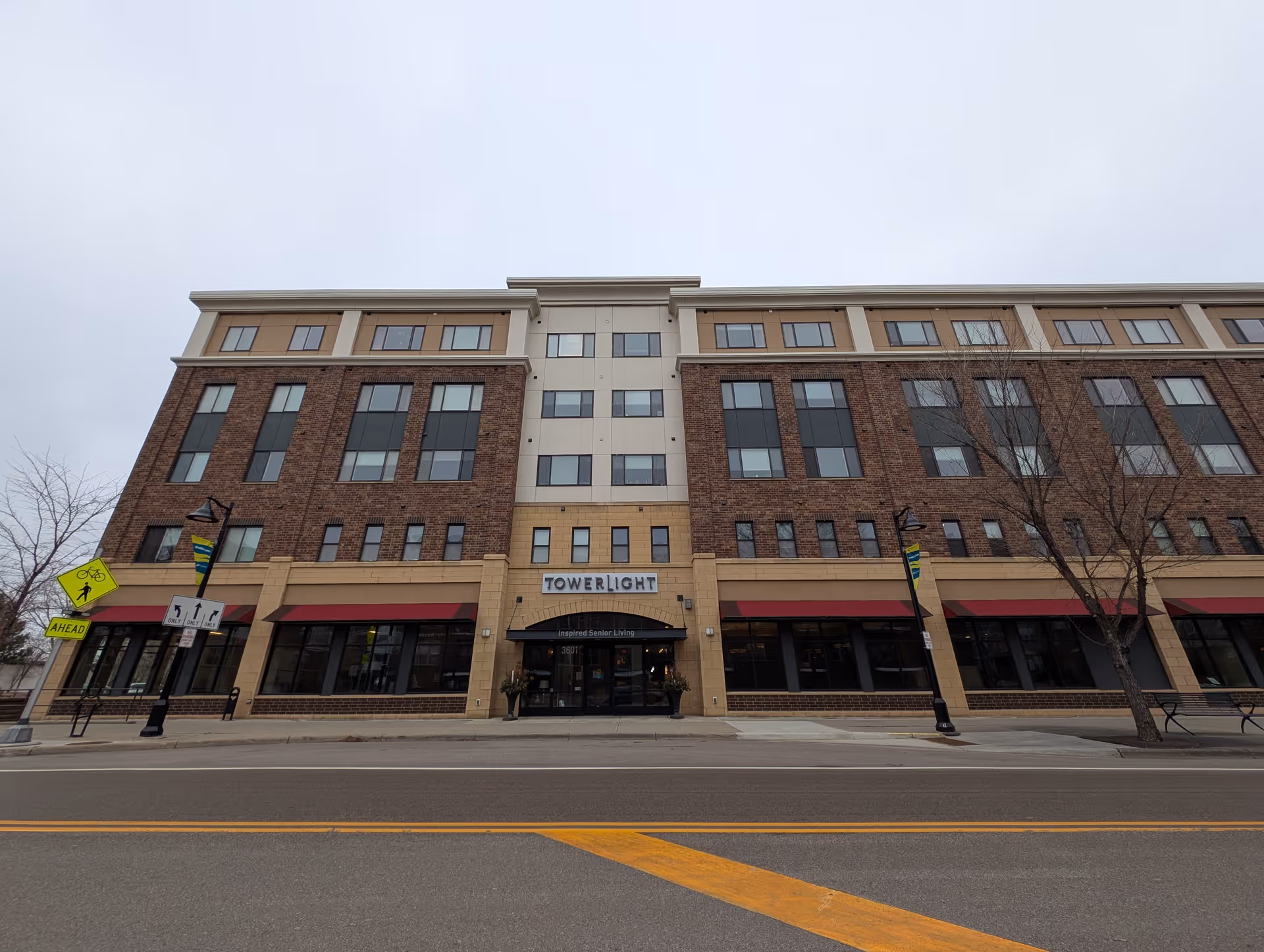 Front exterior of a multi-story brick building with a sign reading "Towerlight" above the main entrance on a cloudy day.