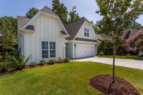 A residential-style senior living building with a white exterior and a two-car garage.