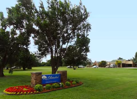 Well-kept grassy front yard with a blue Glenwood sign and distant facility building.