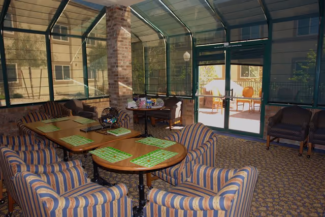 Indoor lounge area with striped chairs around tables in a glass-enclosed communal room.