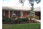 Brick, single-story facility exterior with landscaping and windows along the front.