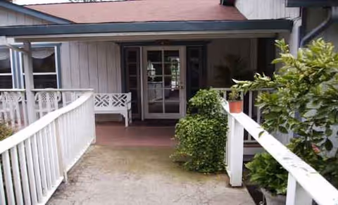 Front entrance of Meadowview Manor with white railing, porch, and potted plants.