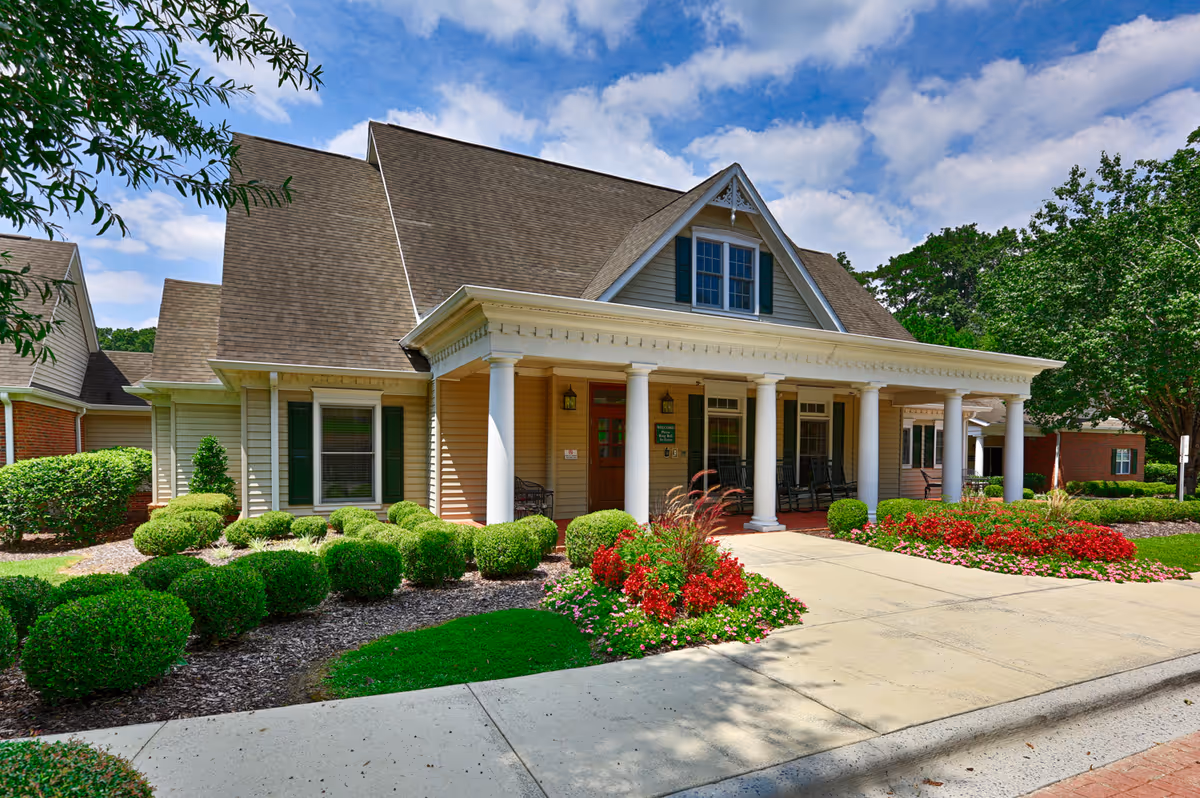 Front view of The Brook senior living facility with porch, columns, and landscaped grounds
