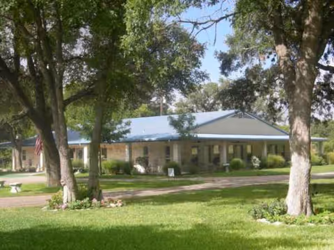 Front exterior of Pafford Place nursing home, a single-story building with a blue roof and trees.