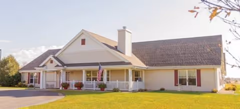 Front view of a single-story senior living facility with porch and flag.