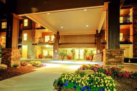 Nighttime entrance to MorningStar Senior Living Boise with stone pillars and flowering landscaping.