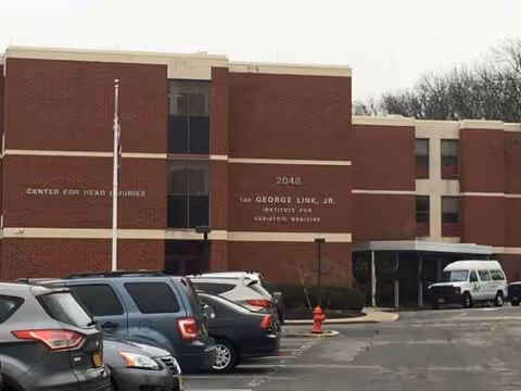 Exterior brick building with parked cars in a front parking lot.