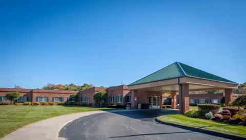 Senior living facility exterior with brick building, driveway, and porte-cochere canopy.