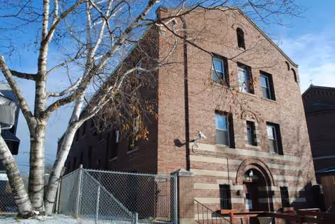 Brick exterior of Parsons House facility front, with bare trees and a metal fence.