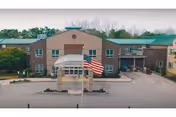 Exterior front of Mcauley Residence with flag and glass entry.