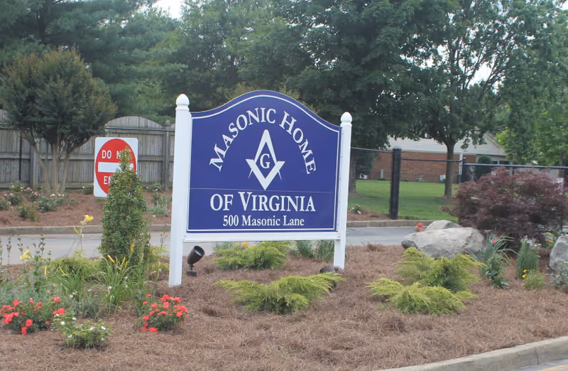 Entrance sign reading "Masonic Home of Virginia, 500 Masonic Lane" surrounded by landscaping and trees.