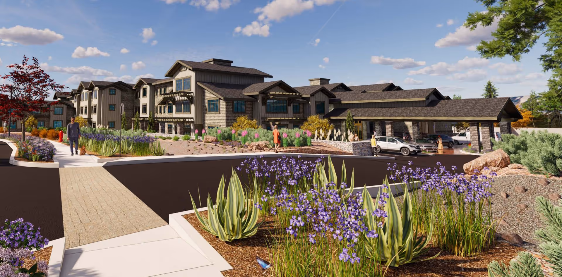 Landscaped driveway and entrance of a multi-story senior living building with purple flowers, people walking, and cars at a covered porte-cochere.