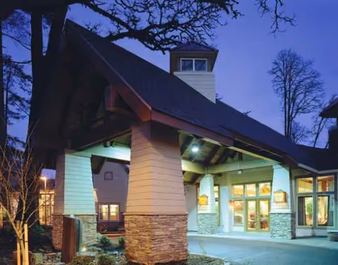 Front view of The Pearl at Kruse Way entrance with illuminated pillars and glass doors.