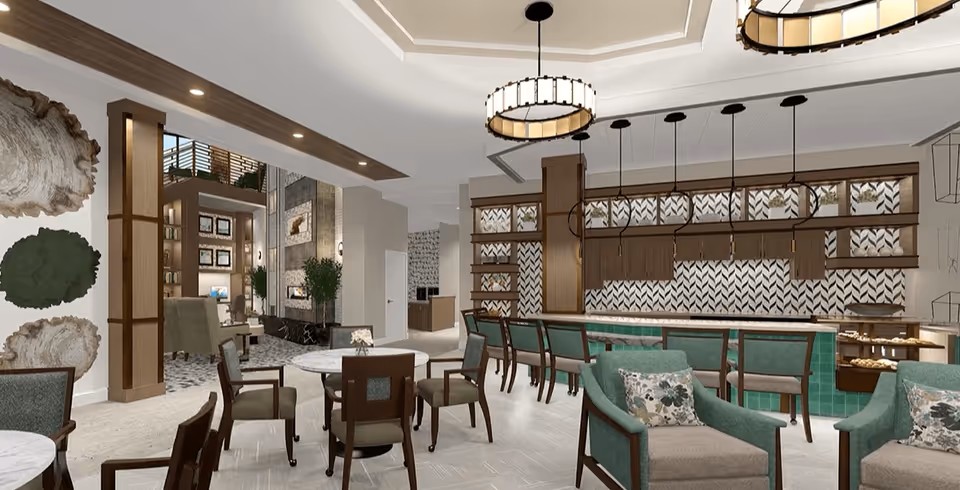 Open communal lounge and dining area with tables, upholstered chairs, and a service bar under decorative lighting.