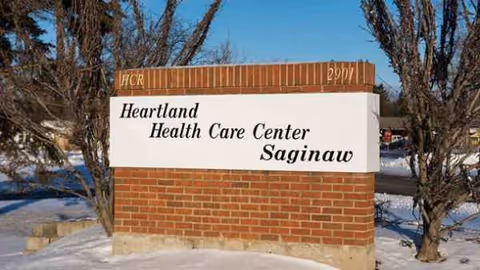Brick sign for Heartland Health Care Center Saginaw in a snowy landscape.