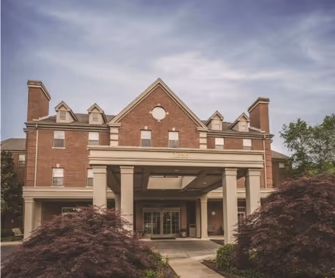 A two-story brick building with an entrance canopy and landscaped surroundings.