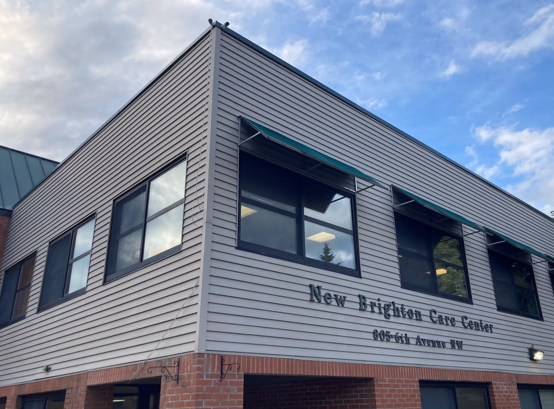 Corner exterior of the New Brighton Care Center building with windows and its name on the facade.