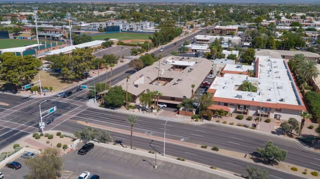 Aerial view of a low-rise senior living/medical complex next to a busy intersection with surrounding streets, parking, and nearby buildings.
