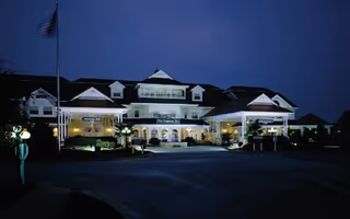 The Huntingdon senior living facility building illuminated at night with a flagpole and entrance canopy visible.