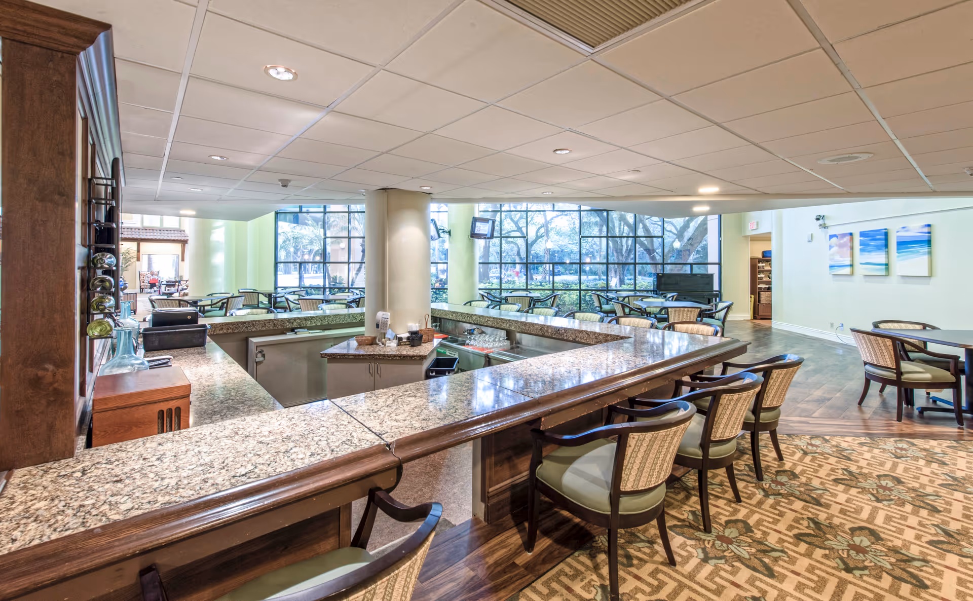 Spacious indoor dining/lounge area with a granite-topped service counter, bar seating, and tables by large windows.